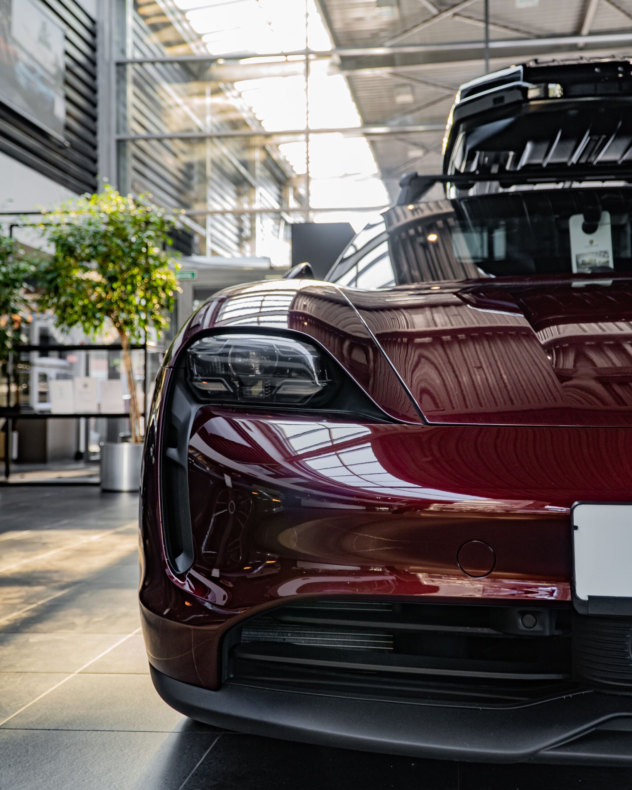 Close-up of a luxury sports car with open hood in a sleek, modern showroom setting.