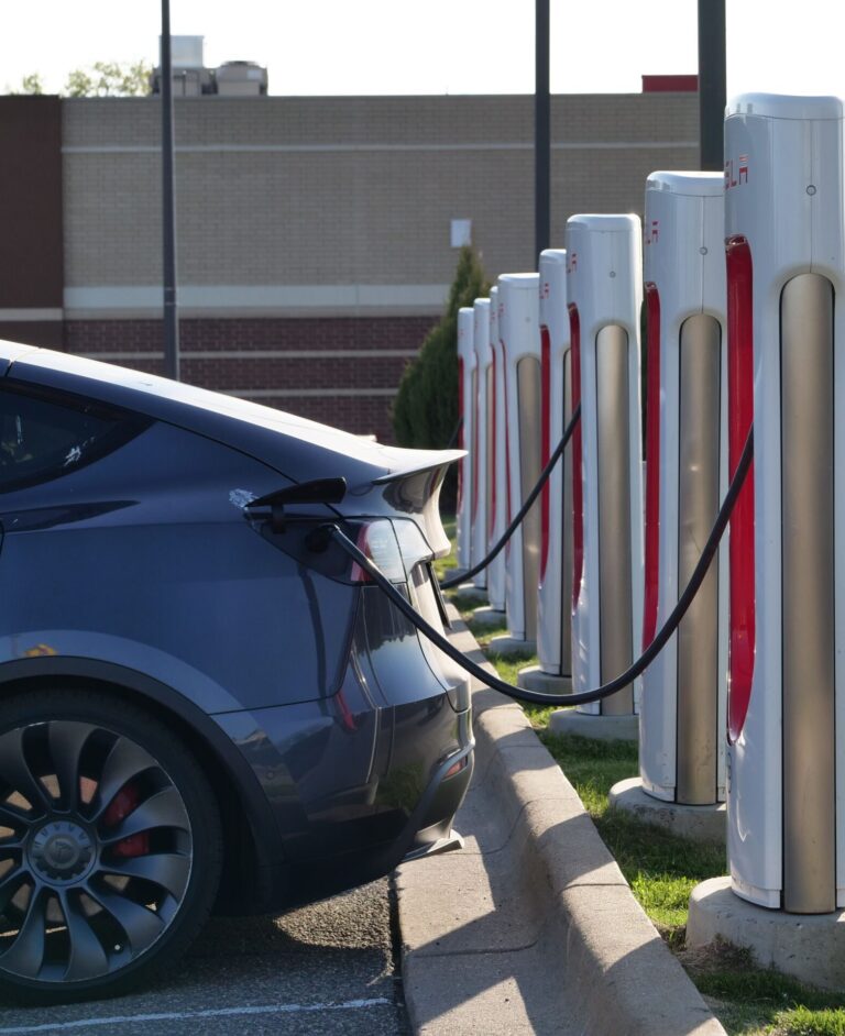 Electric car plugged into a row of charging stations, showcasing modern EV infrastructure.
