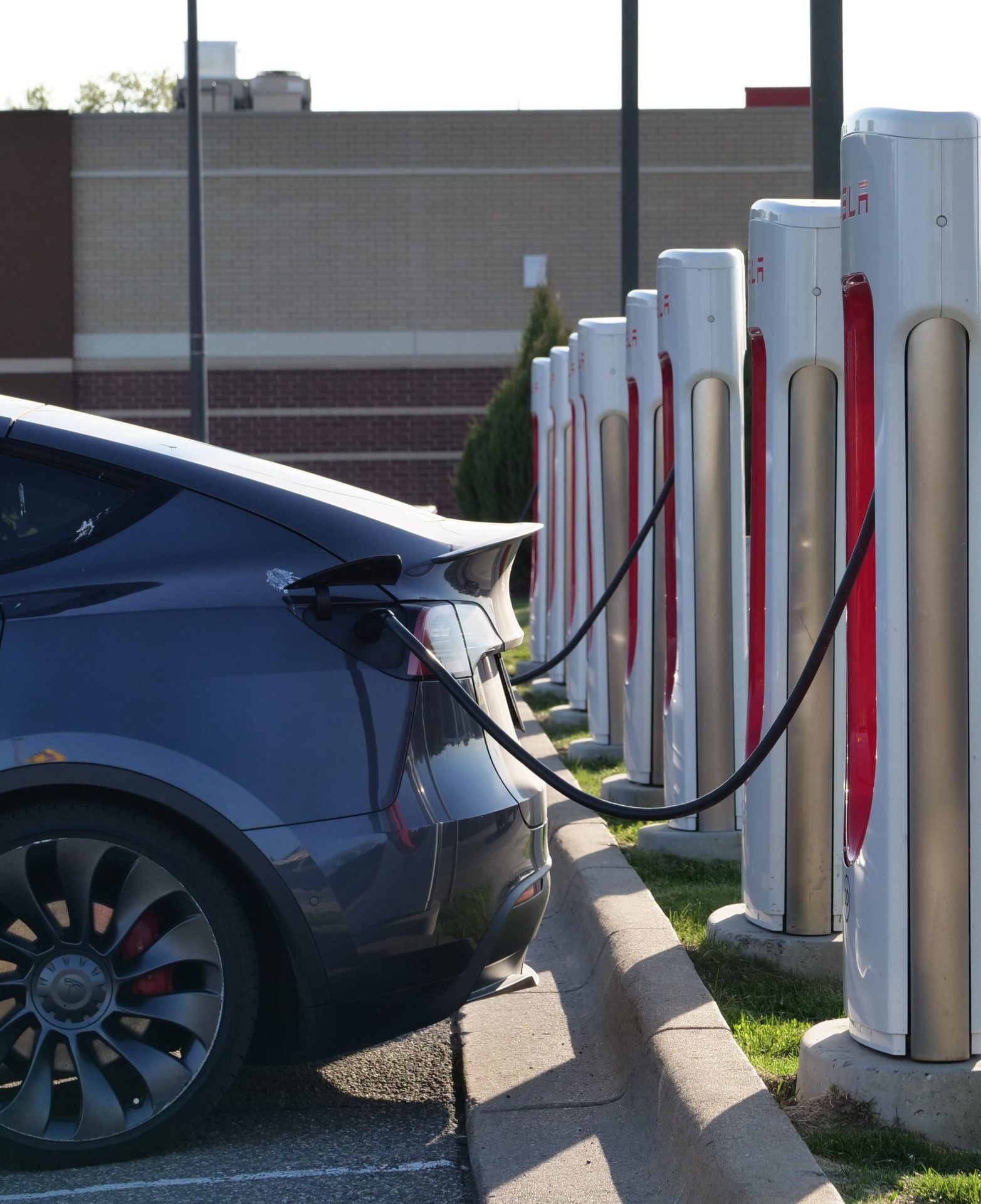 Electric car plugged into a row of charging stations, showcasing modern EV infrastructure.